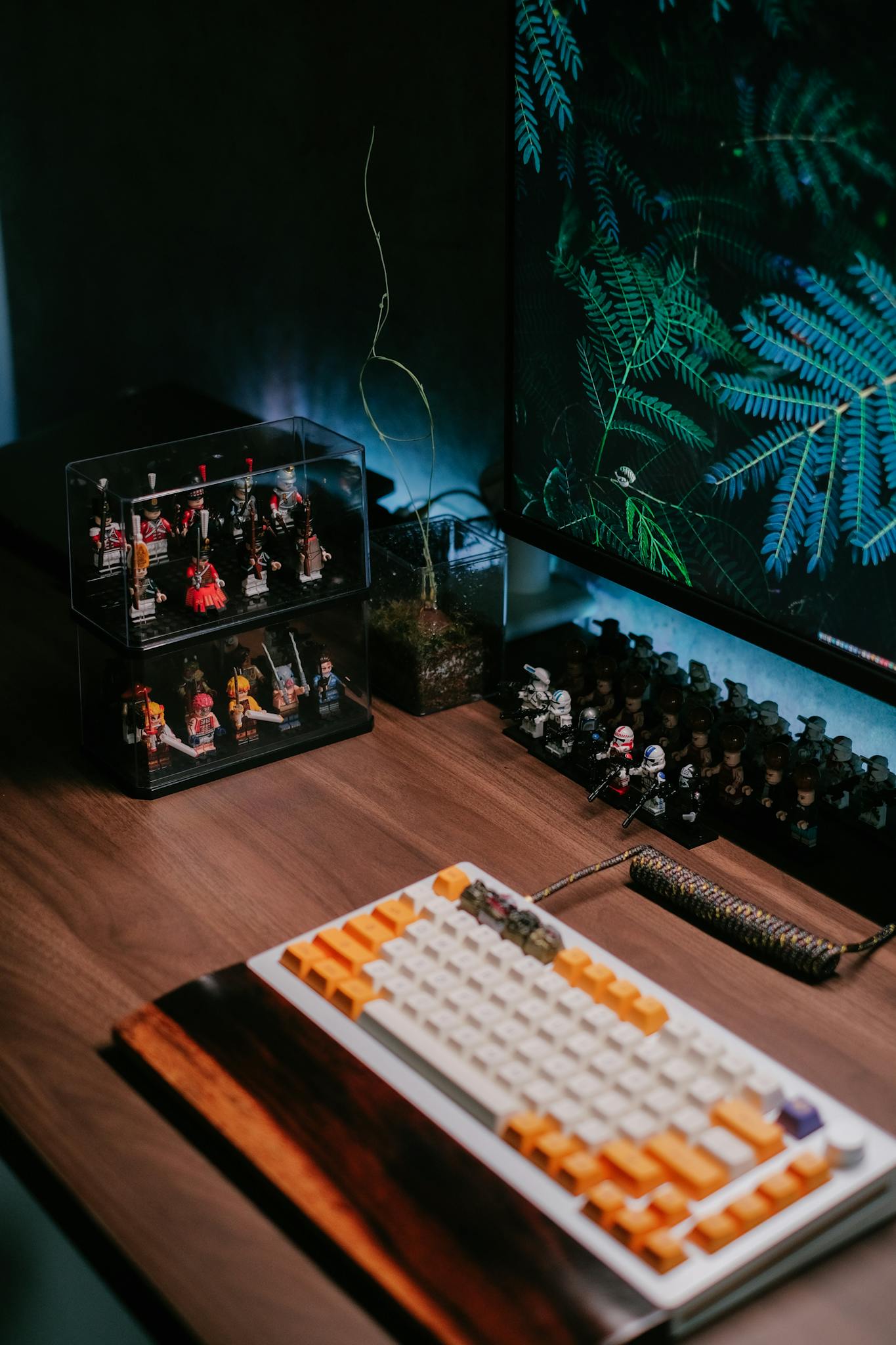 A neat desk setup featuring collectible figurines, computer keyboard, and vibrant monitor display.